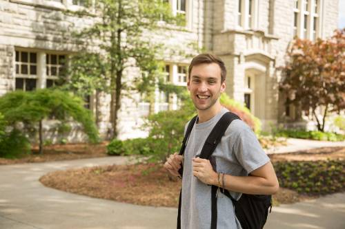 student smiling in front of admin building