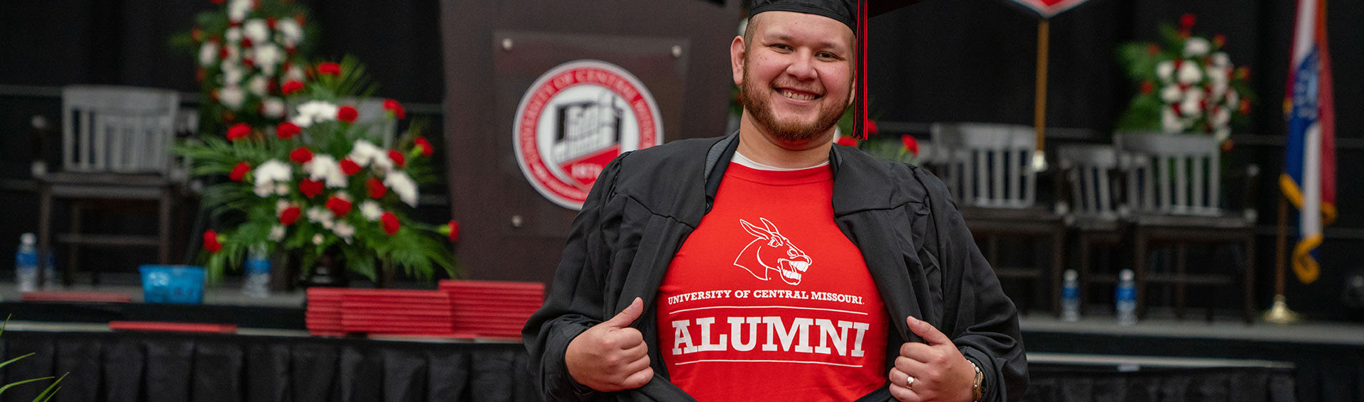 A UCM alum showing their alumni shirt at Commencement